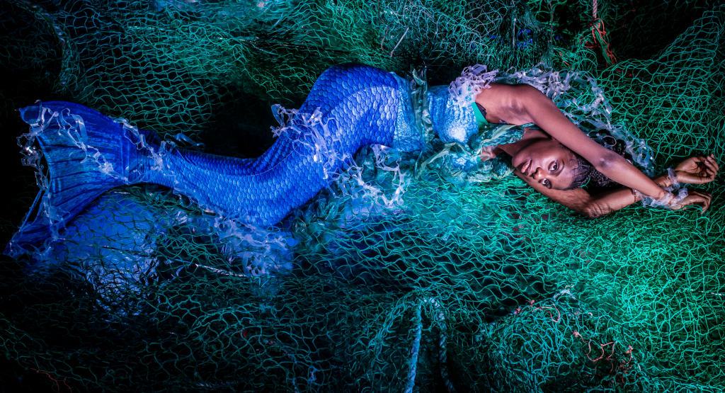 mermaid in netting with brown skin and a blue tail